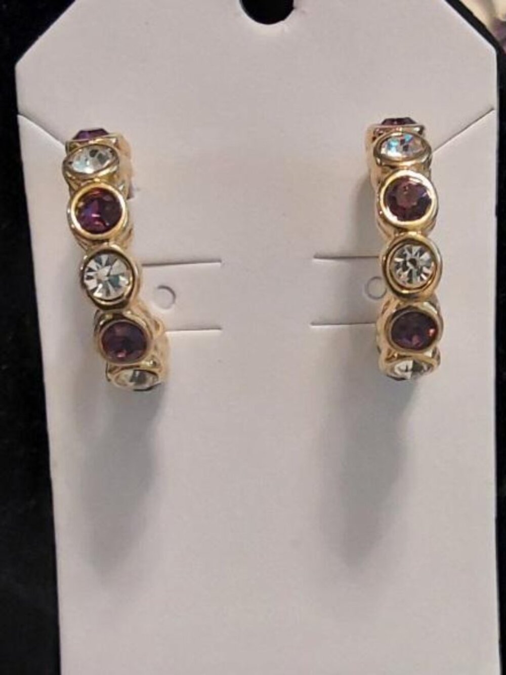 Gold-tone half hoop post earrings with alternating purple and clear stones.